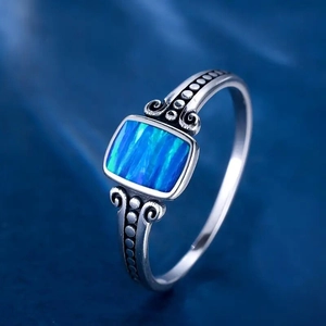 Macro shot of silver ring featuring square blue opal with vintage engraved details