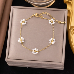Detailed shot of gold titanium bracelet featuring five white pearl flower charms on display