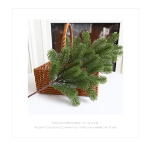 Realistic green PE pine branch leaning against a woven basket by a cozy fireplace