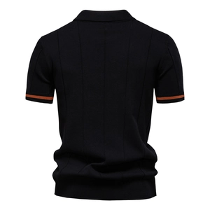 Vista posteriore dettagliata della polo in maglia nera con polsini a righe arancioni e texture