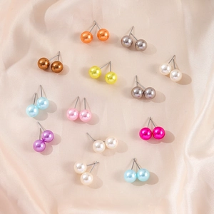 Set of 15 pairs of colorful imitation pearl stud earrings on soft beige silk fabric