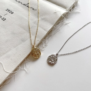 Detailed view of textured gold and silver organic pendants on modern minimalist chains