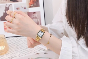 Elegant gold square quartz watch with Roman numerals and matching jewelry set worn by model