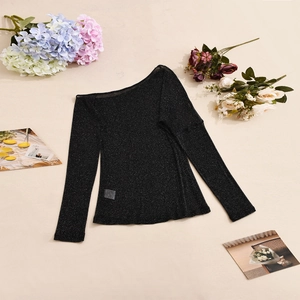 Détail d'un haut noir scintillant à manches longues et col bardot avec texture en Lurex