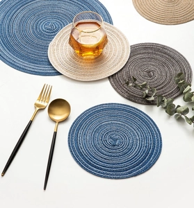 Detailed view of round woven heat-resistant placemats in blue, beige, and dark grey tones