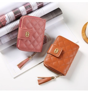 Détail de portefeuilles courts matelassés en rose et marron avec glands et décor doré