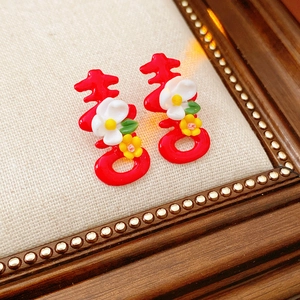 Close-up of red Double Happiness character earrings with floral details and green leaves