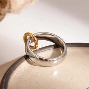 Dettaglio di anelli intrecciati in acciaio inossidabile argento e oro su ceramica