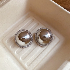 Macro shot of silver round stud earrings with polished mirror surface and rhinestone halo