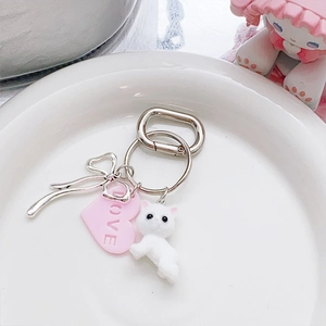 Dettaglio portachiavi con gatto floccato, cuore rosa love e fiocco metallico