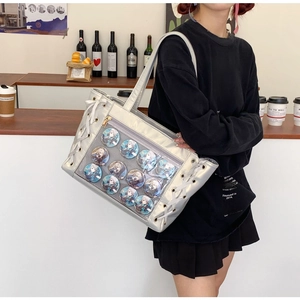 Detail of a large silver ita-bag with transparent window displaying anime pins in a cafe