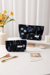 Detailed close-up of premium black linen cosmetic bags with blue floral embroidery