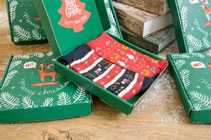 Close-up of red and navy blue Christmas socks in a gift box on a snowy wood background