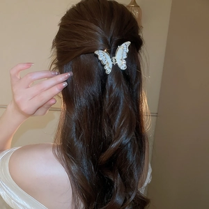 Dettaglio elegante molletta per capelli a farfalla con zirconi su capelli ondulati