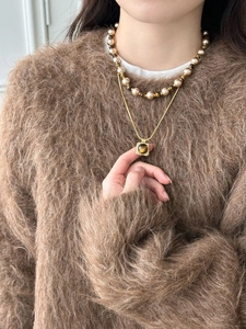 Close-up of layered tiger eye pendant necklace and pearl bead chain on model