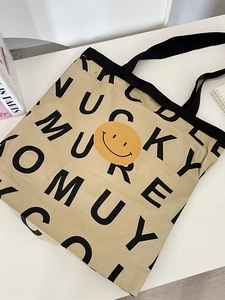 Canvas tote bag with smiley face and letter print on a stylish desk setting