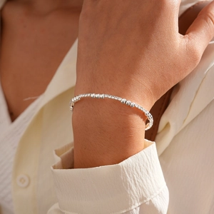 Close-up of a silver beaded bangle with rhinestones on a woman's wrist in a minimalist style