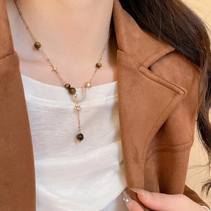 Detail of tiger eye stone necklace with gold crescent moon and star zircon pendants