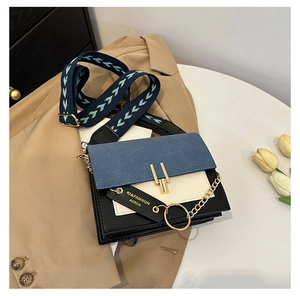 Detail of color-block crossbody bag with gold buckle and textured wide shoulder strap
