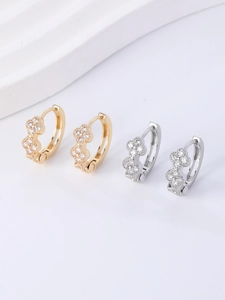 Close-up of gold and silver huggie earrings with sparkling CZ flower charms