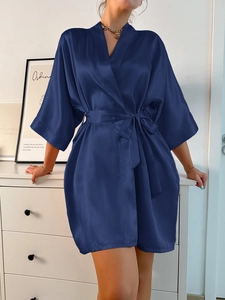 Détail d'un peignoir en satin bleu marine avec manches amples et ceinture assortie