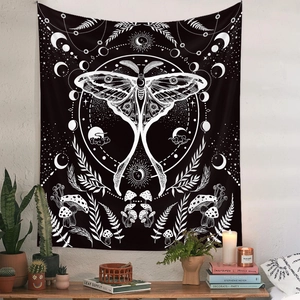 Detailed view of bohemian black and white moth tapestry hanging on white wall with plants