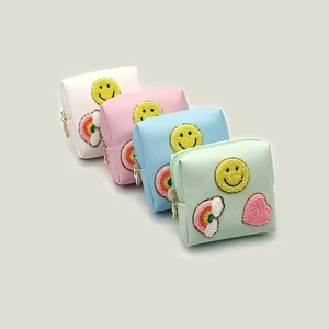 Detailed view of four colorful PU leather cosmetic pouches with chenille patches