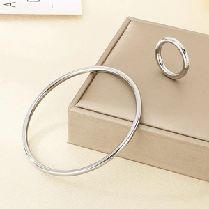 Close-up of polished silver stainless steel bracelet and ring set on a texture box