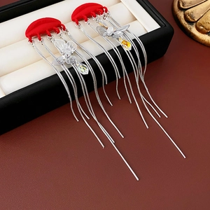 Detail of red lip earrings with silver tassels, butterfly charms, and teardrop zircon