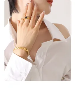Detail of gold watchband bracelet and chain rings with a smiley face on a model hand