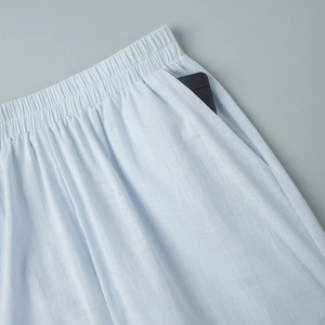Detail view of cotton trousers with elastic waist and pocket holding a phone