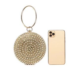 Macro view of gold rhinestone evening bag with round handle showing size compared to phone