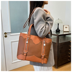 Detail of vintage brown patchwork tote bag with zipper accents and pebble leather texture