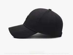 Side view of a black baseball cap with textured fabric and a circular metal logo badge