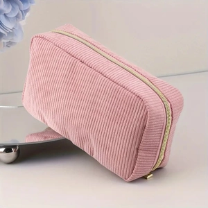 Pink corduroy large capacity makeup bag with gold zipper on a mirrored stand