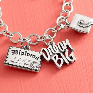 Detailed close-up of stainless steel graduation charms featuring Diploma and Dream BIG plates