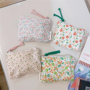 Detail view of four mini floral canvas pouches with zip closures and woven pull tabs