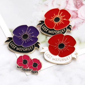Detailed view of red poppy enamel pins featuring Lest We Forget and Try Burning These text