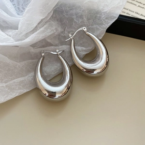 Macro view of silver U-shaped metal earrings with high-polish mirror finish and smooth curve
