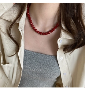 Détail d'un collier de perles rouges porté sur un modèle pour un look vintage français épuré