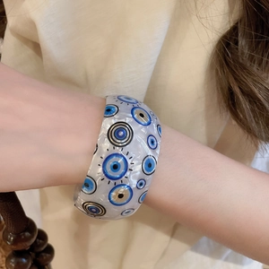 Detailed shot of iridescent acrylic evil eye bangle with pearl-like texture and patterns