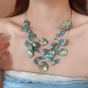 Multilayer beaded necklace with iridescent shell pendants and blue crystal accents