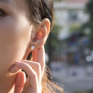 Close-up of cute cat ear stud earrings with white pearls worn on a female ear model