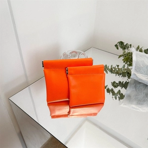 Mini orange PU leather snap top coin purses in two sizes on a reflective surface