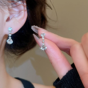 Detail of elegant silver circular drop earrings with sparkling diamonds on a model