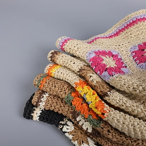Detail of multi-colored hand-crocheted straw hats with intricate floral knitting patterns