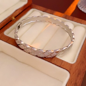 Detailed view of silver rhombic pattern bangle with pavé zircons in a jewelry box