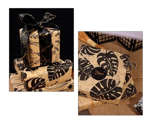 Detail of kraft wrapping paper with leaf and marble prints on a gift box with black ribbon
