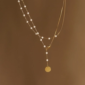 Elegant gold double-layered pearl Y-necklace with round pendant on warm background