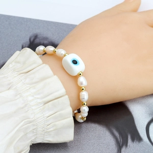 Detailed close-up of natural freshwater pearl bracelet with lucky blue evil eye charm